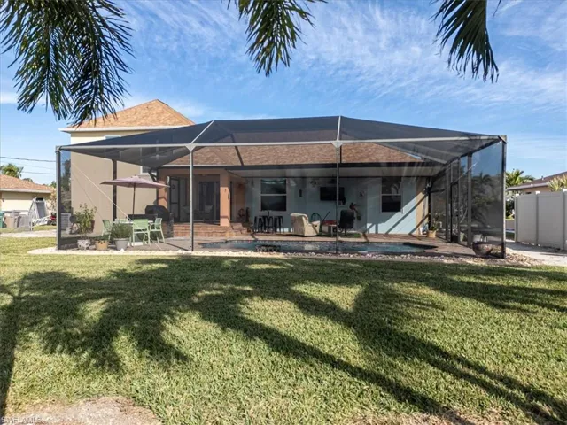 Back of property with a lawn, a patio area, and glass enclosure