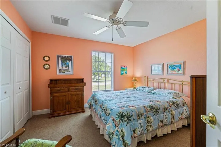 Bedroom with ceiling fan, light colored carpet, and a closet