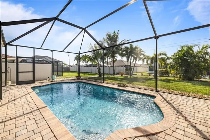 View of swimming pool featuring glass enclosure, a patio area, and a lawn