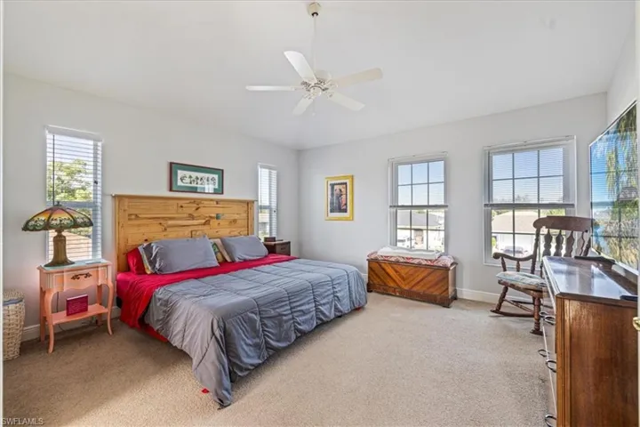 Bedroom featuring multiple windows, ceiling fan, and light carpet