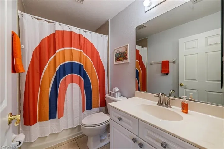Full bathroom featuring vanity, tile patterned flooring, toilet, shower / bath combo with shower curtain, and a textured ceiling