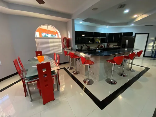 Tiled dining space featuring a raised ceiling and sink