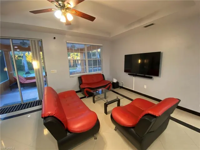 Tiled living room with ceiling fan and a raised ceiling