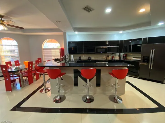 Kitchen with a center island with sink, a kitchen breakfast bar, a raised ceiling, and stainless steel fridge with ice dispenser