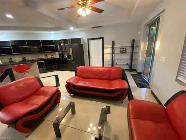 Living room featuring a tray ceiling, ceiling fan, and light tile patterned flooring