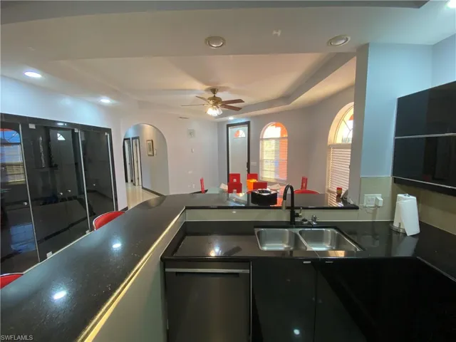 Kitchen featuring dishwasher, a tray ceiling, ceiling fan, and sink