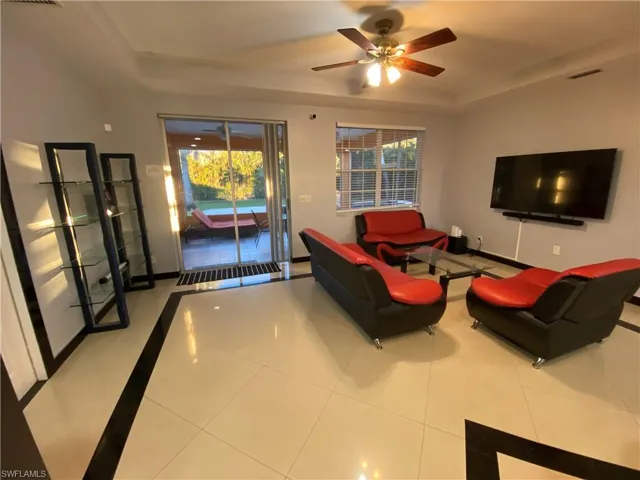 Living room featuring tile patterned flooring, a raised ceiling, and ceiling fan