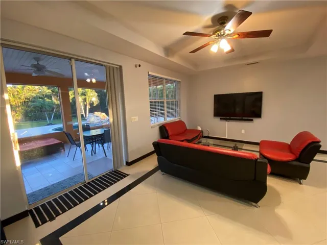 Tiled living room featuring a tray ceiling and ceiling fan