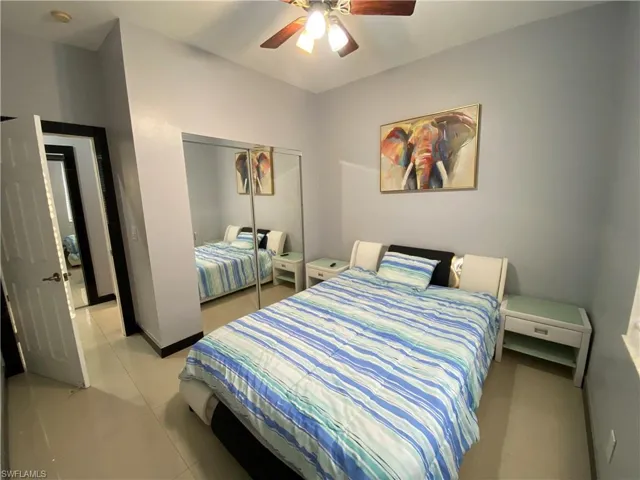 Bedroom with ceiling fan, a closet, and light tile patterned flooring