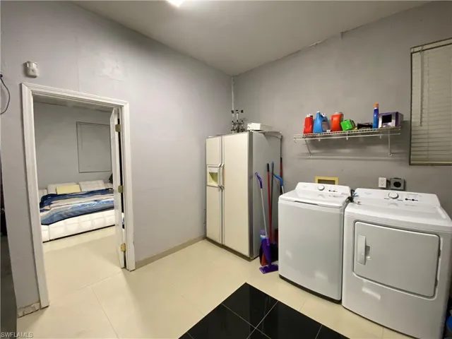 Washroom featuring light tile patterned floors and washing machine and clothes dryer