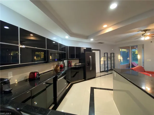 Kitchen featuring a tray ceiling, light tile patterned floors, and refrigerator with ice dispenser