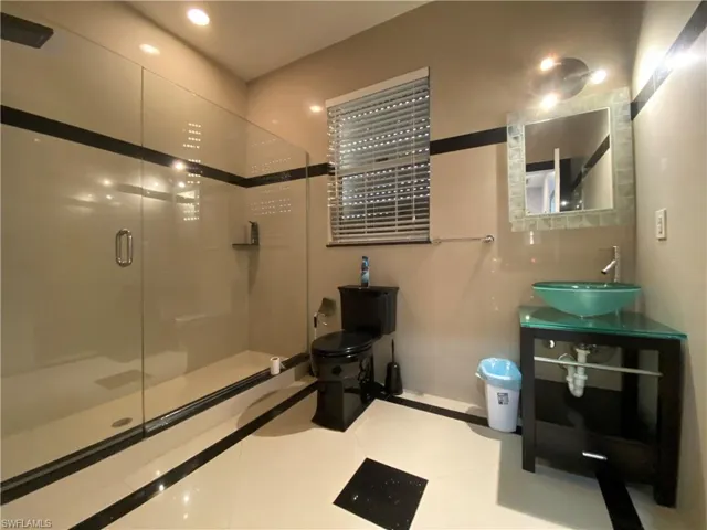 Bathroom featuring toilet, vanity, tile patterned floors, and an enclosed shower