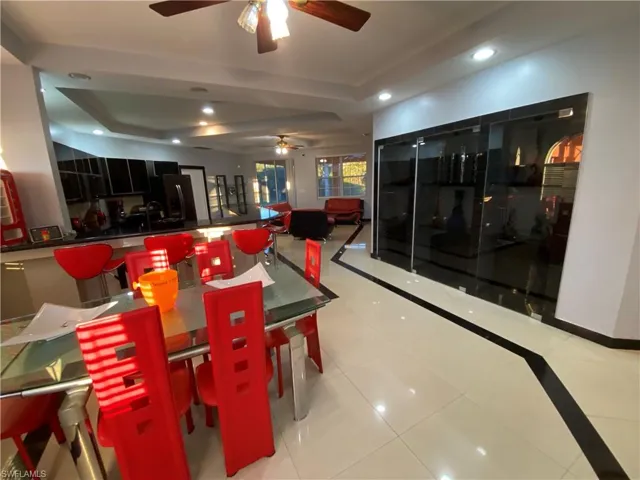 Dining area with a tray ceiling, ceiling fan, and light tile patterned floors