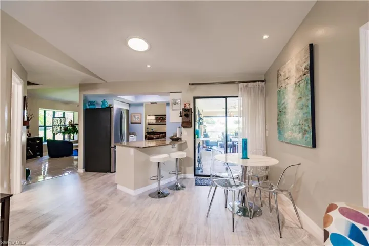 Kitchen with light wood-type flooring, kitchen peninsula, stainless steel fridge, and a breakfast bar
