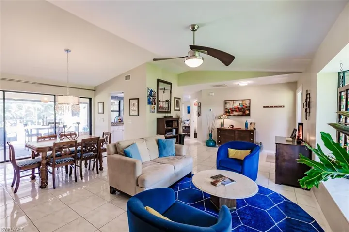 Living room featuring ceiling fan, lofted ceiling, and light tile patterned flooring