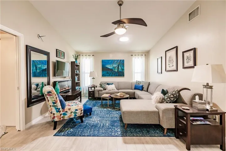 Living room with ceiling fan, vaulted ceiling, and light hardwood / wood-style floors