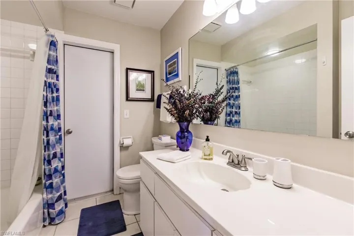 Full bathroom with tile patterned floors, toilet, shower / tub combo with curtain, and vanity