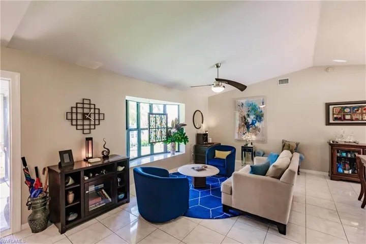 Tiled living room featuring ceiling fan and vaulted ceiling and beautiful bay window