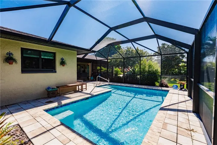 View of swimming pool featuring glass enclosure and a patio area