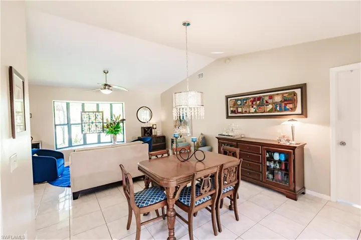 Tiled dining area with ceiling fan and lofted ceiling