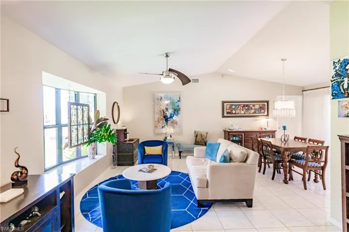 Living room featuring ceiling fan, light tile patterned floors, and lofted ceiling