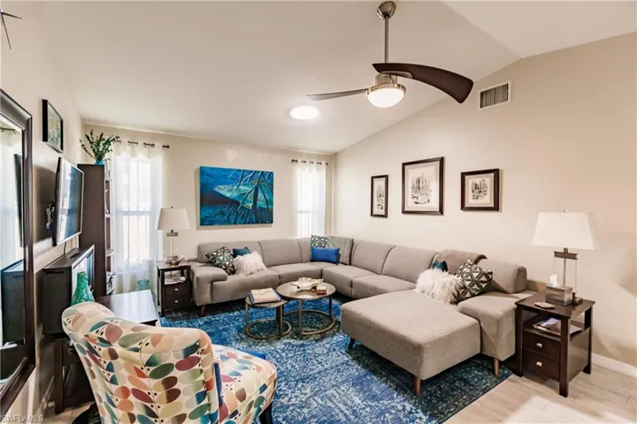 Living room with light hardwood / wood-style flooring, ceiling fan, and vaulted ceiling