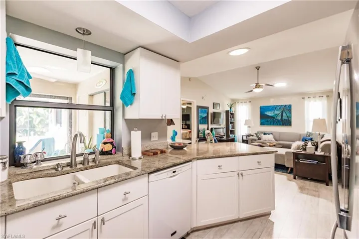 Kitchen featuring white cabinets, light stone counters, white dishwasher, and ceiling fan