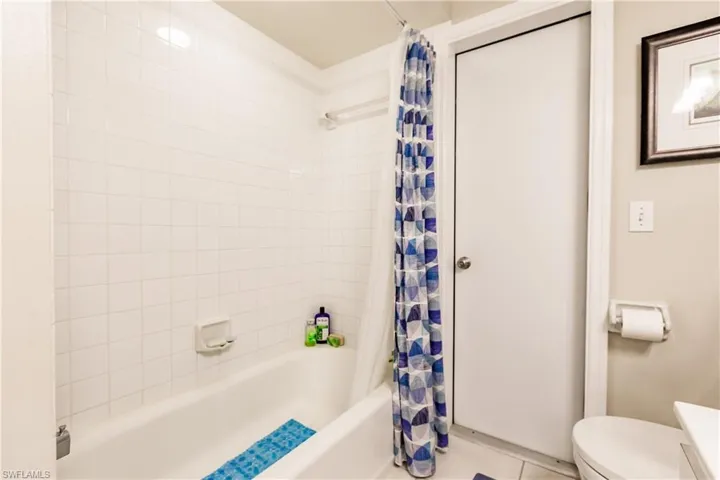 Bathroom with shower / bath combination with curtain, toilet, and tile patterned floors