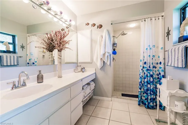 Bathroom featuring tile patterned flooring, curtained shower, plenty of natural light, and vanity