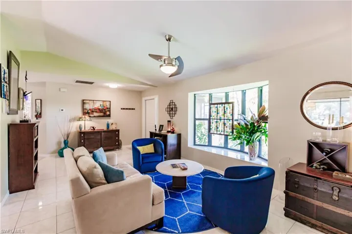 Tiled living room with ceiling fan and vaulted ceiling
