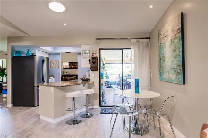 Kitchen featuring a kitchen breakfast bar, stainless steel refrigerator, light hardwood / wood-style floors, stone counters, and kitchen peninsula