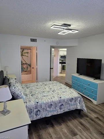 Bedroom with dark wood-style flooring and a textured ceiling