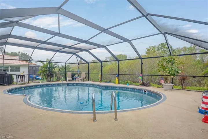 Swimming pool featuring glass enclosure, a sunroom, and a grill