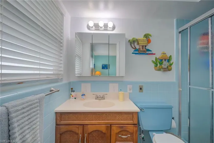 Bathroom featuring wainscoting, vanity, a stall shower, and tile walls