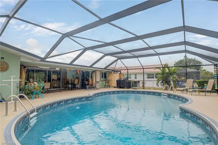 Outdoor pool featuring a sunroom, glass enclosure, and a patio area