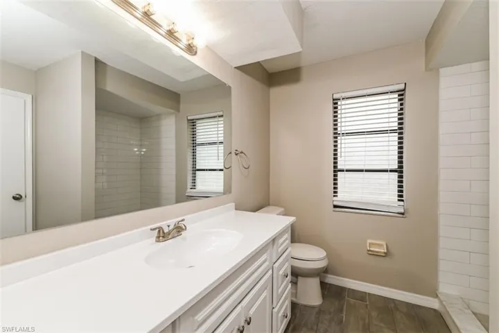 Bathroom featuring vanity, tiled shower, and toilet