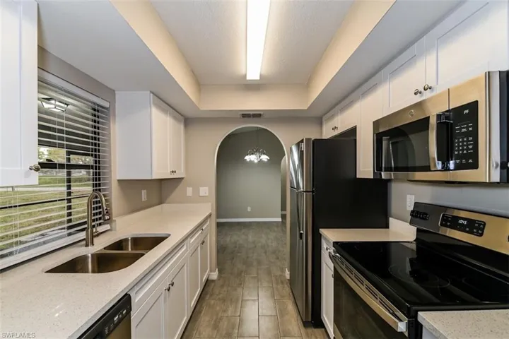 Kitchen featuring white cabinetry, appliances with stainless steel finishes, and a tray ceiling
