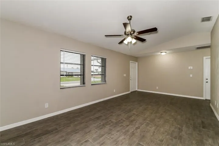 Spare room featuring vaulted ceiling, dark hardwood / wood-style floors, and ceiling fan