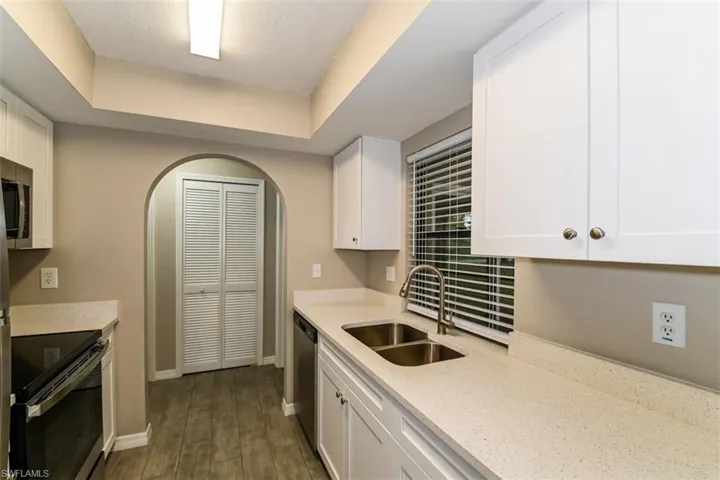 Kitchen with sink, electric range oven, a raised ceiling, and white cabinets