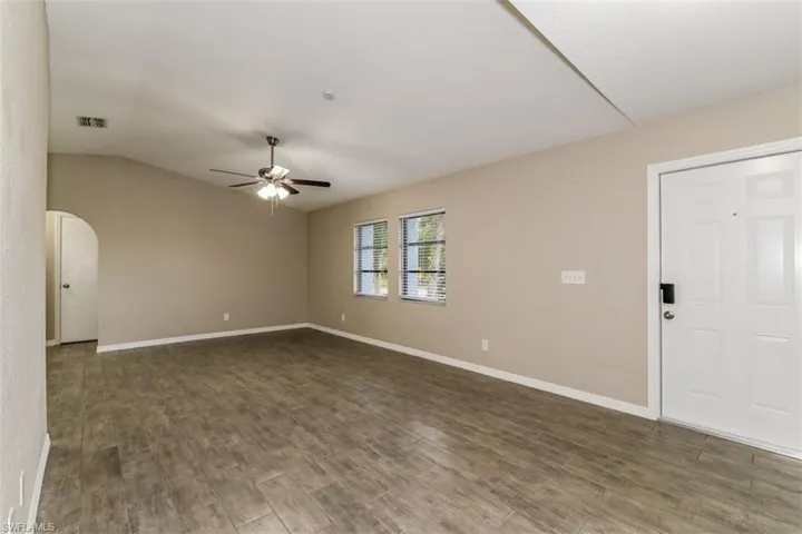 Spare room featuring lofted ceiling, dark wood-type flooring, and ceiling fan