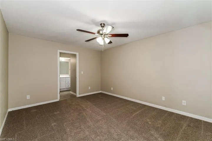Spare room featuring ceiling fan and dark colored carpet