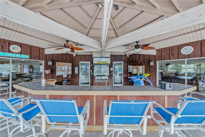 Kitchen featuring lofted ceiling with beams, ceiling fan, and wood walls