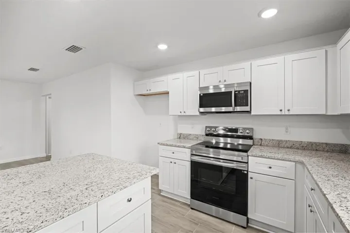 Kitchen featuring stainless steel appliances, white cabinetry, wood tiled floors, and recessed lighting