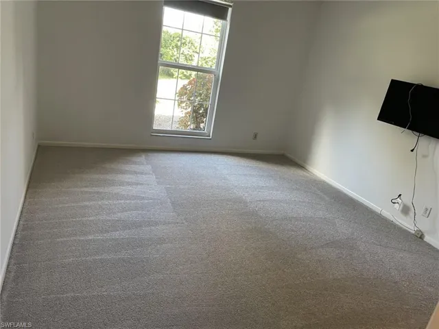 Empty room with light colored carpet and baseboards