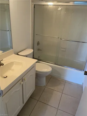 Bathroom featuring vanity, enclosed tub / shower combo, and light tile patterned floors
