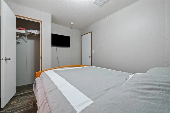 Bedroom with dark wood-style floors, a textured ceiling, and a walk in closet