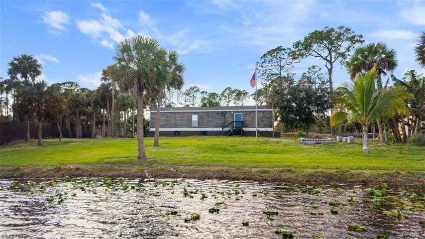 Rear view of house featuring a water view and a lawn