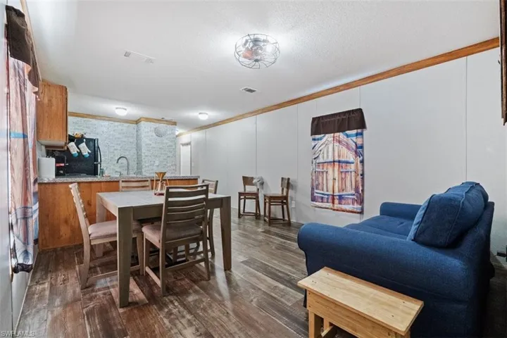 Dining area with ornamental molding, dark wood-type flooring, and a textured ceiling