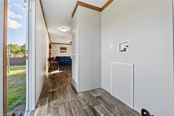 Hallway featuring dark wood-style floors and a decorative wall
