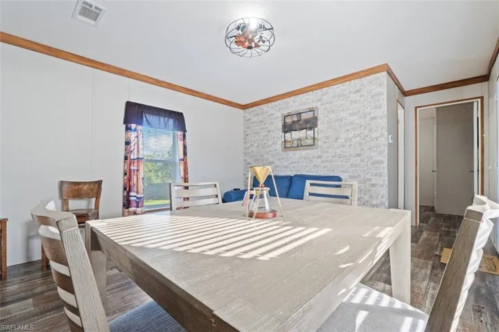 Dining space with ornamental molding and dark wood-style floors